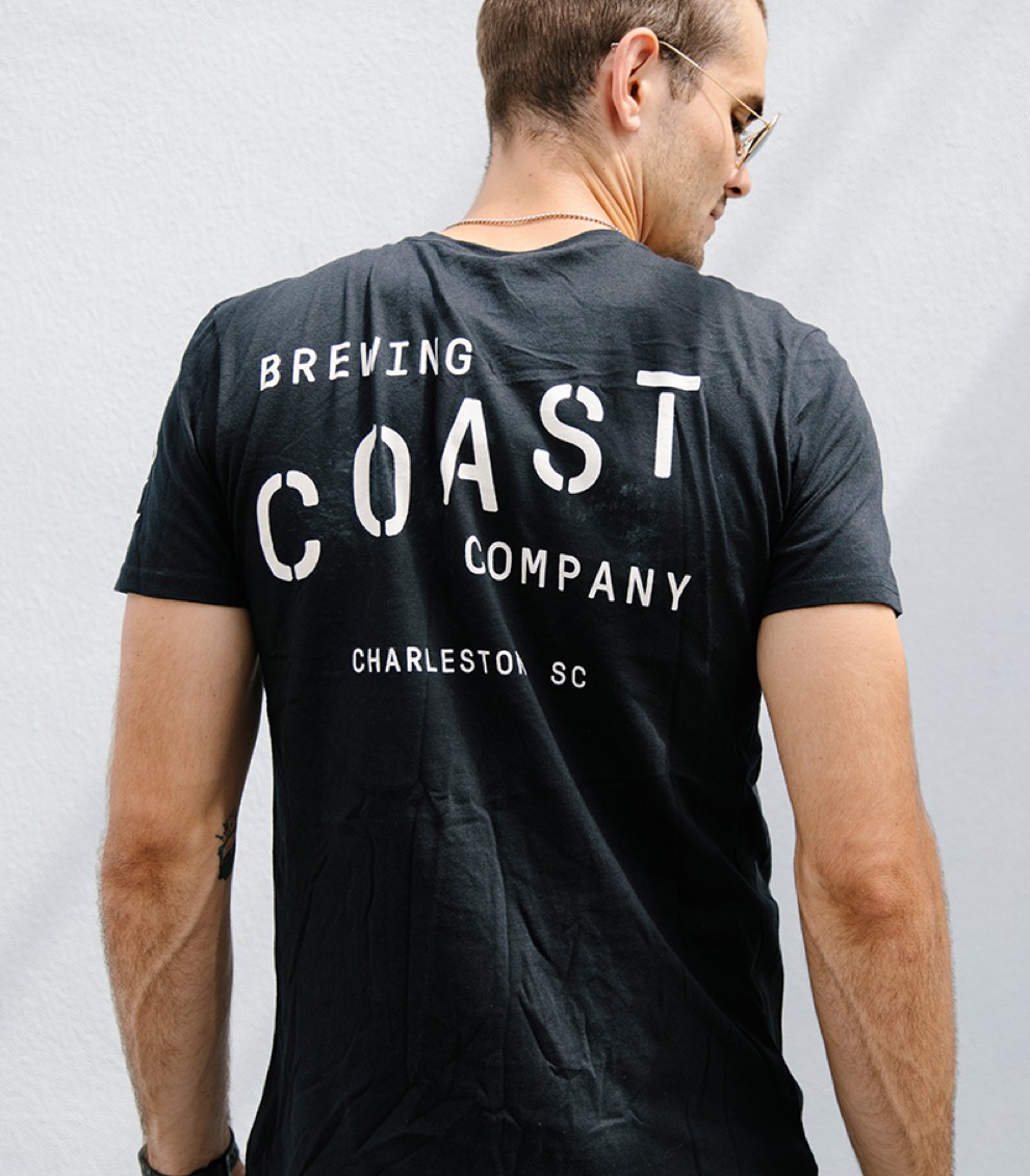 A man wears a trendy black and white brewing company shirt. 