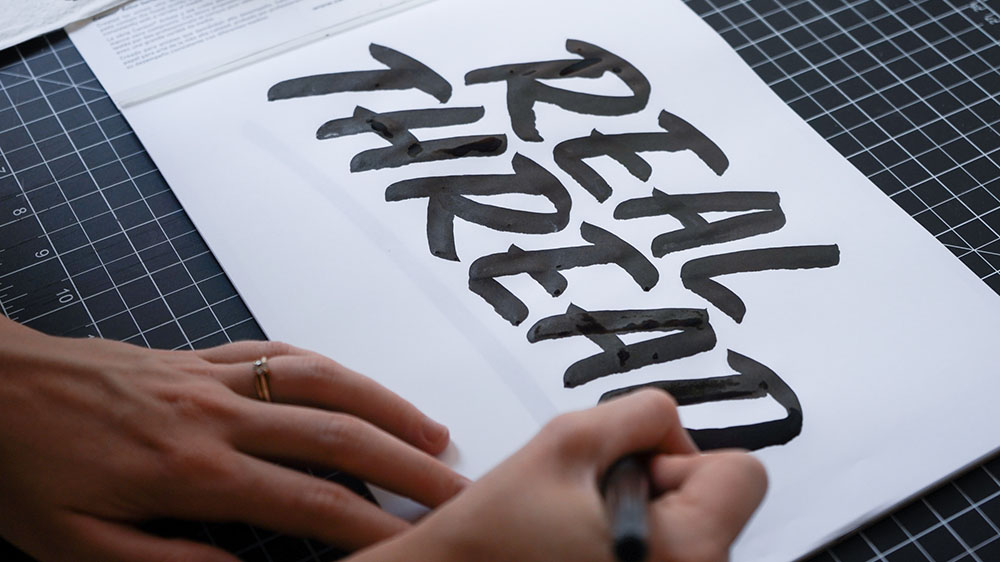 woman hand lettering words in black ink 