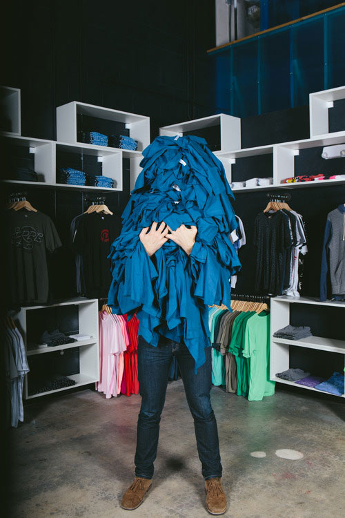 man holding pile of blue shirts