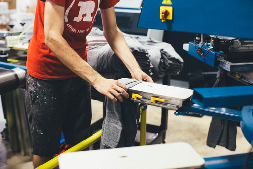 man adjusting shirt on screen press machine
