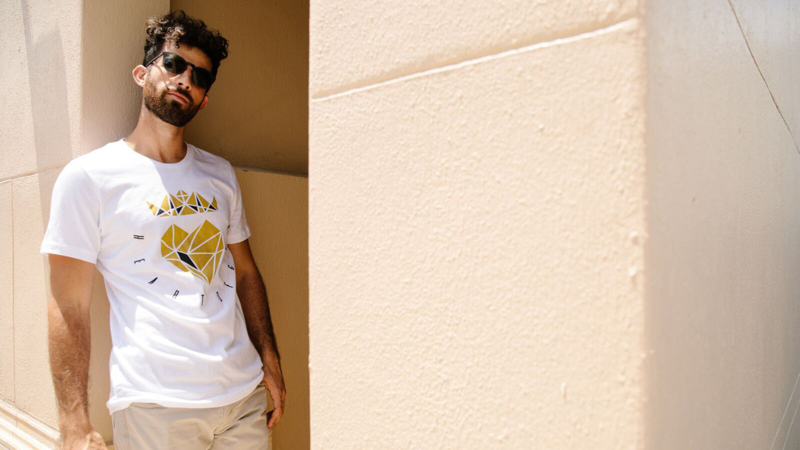 man standing against wall wearing sunglasses 