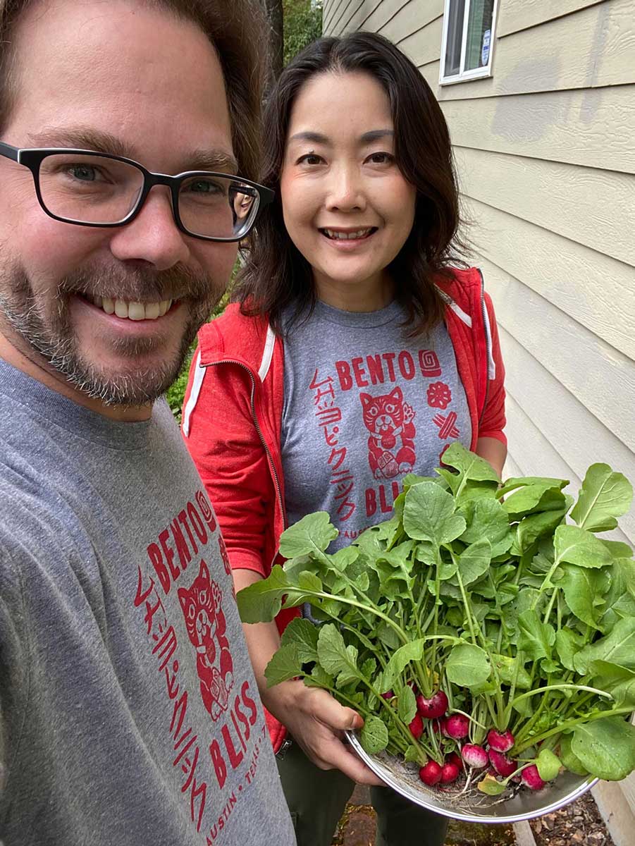 A couple holding a bowl of veggies smiling