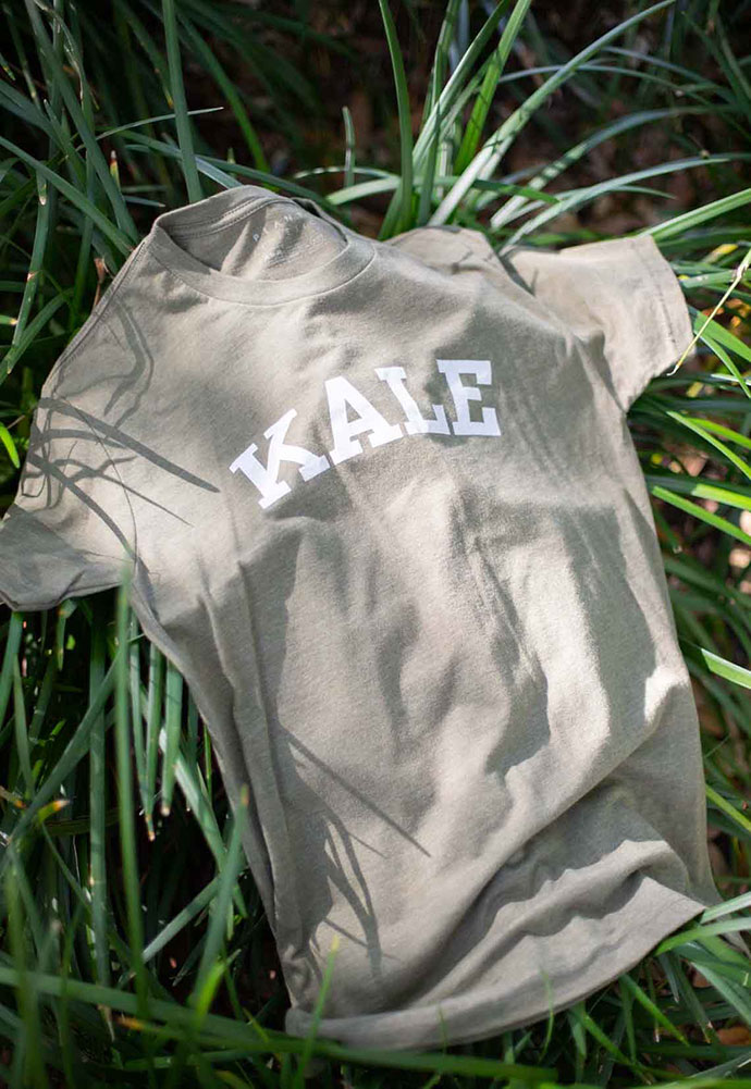 A shirt that reads "kale" is laying artfully in the grass.