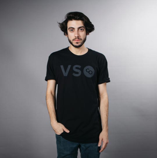 young man standing with black shirt in front of white backdrop 
