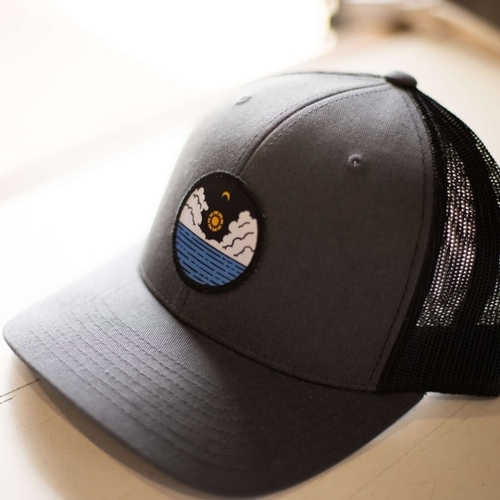 A custom hat with a patch depicting the sun over the ocean.