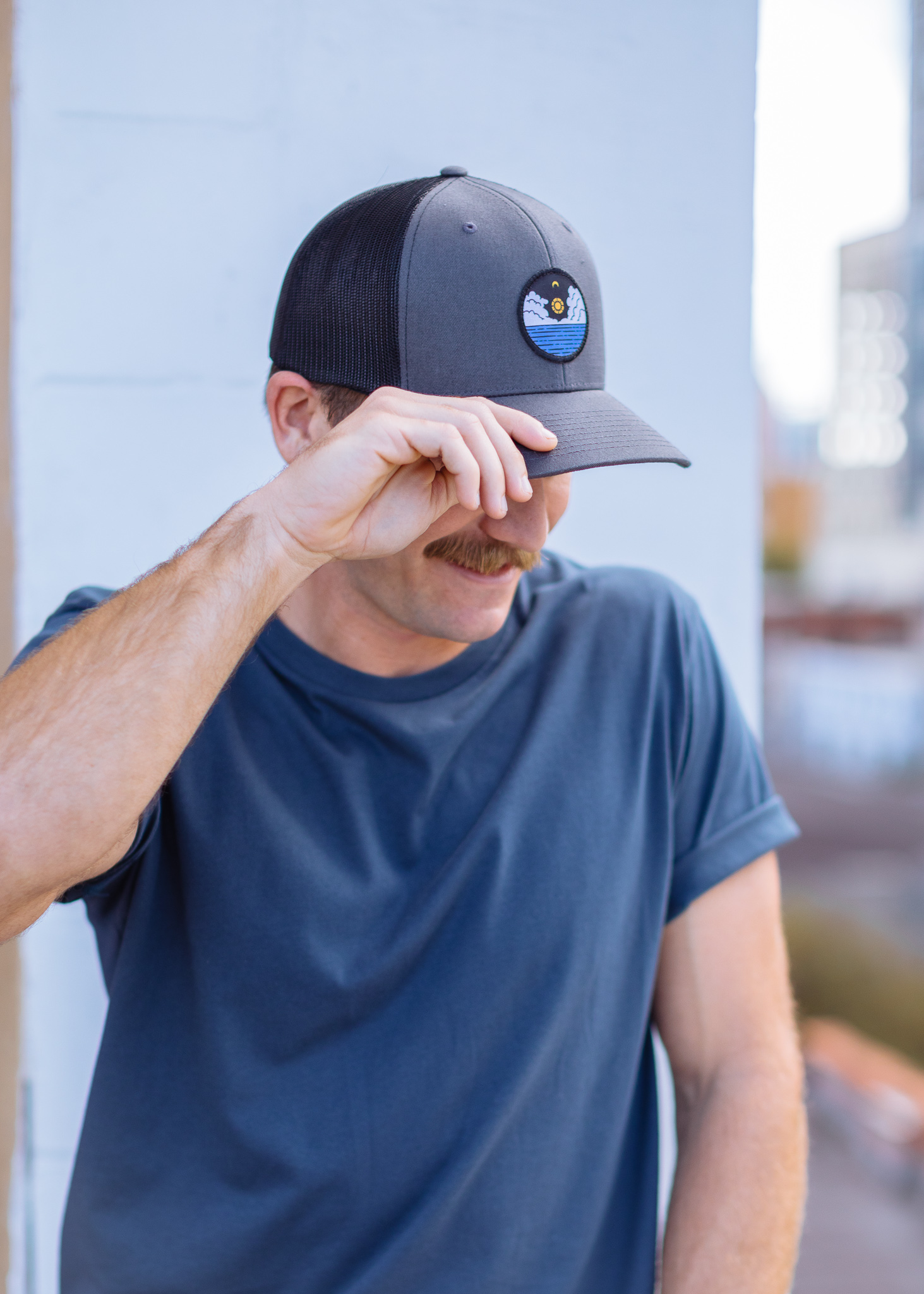 a man wears a hat with a sunset patch on it