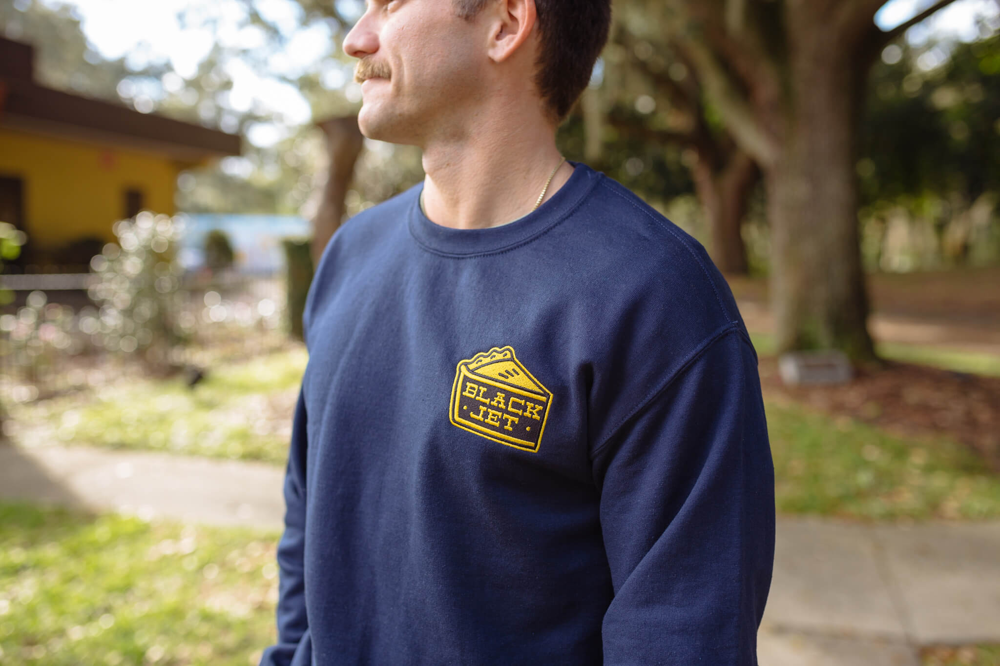 a man wears a custom crewneck sweatshirt with a patch on it