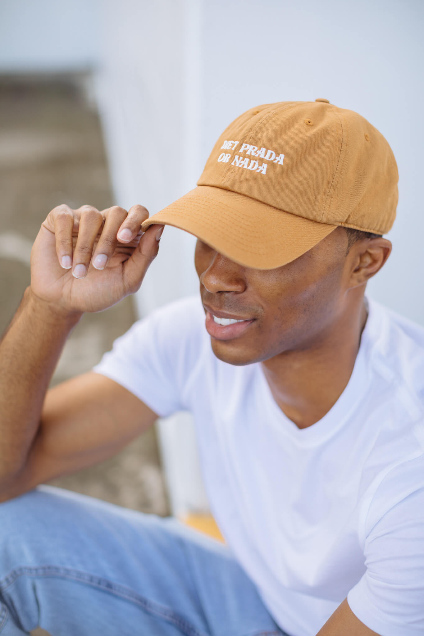 Man wearing a tan baseball cap with white embroidery on it
