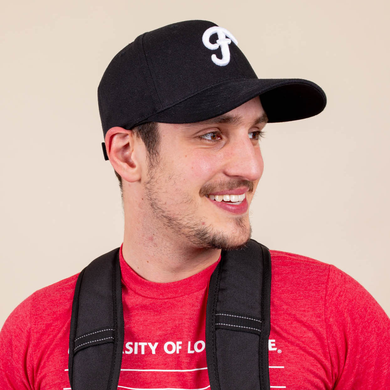 Man wears black snapback hat with white puff embroidery on it