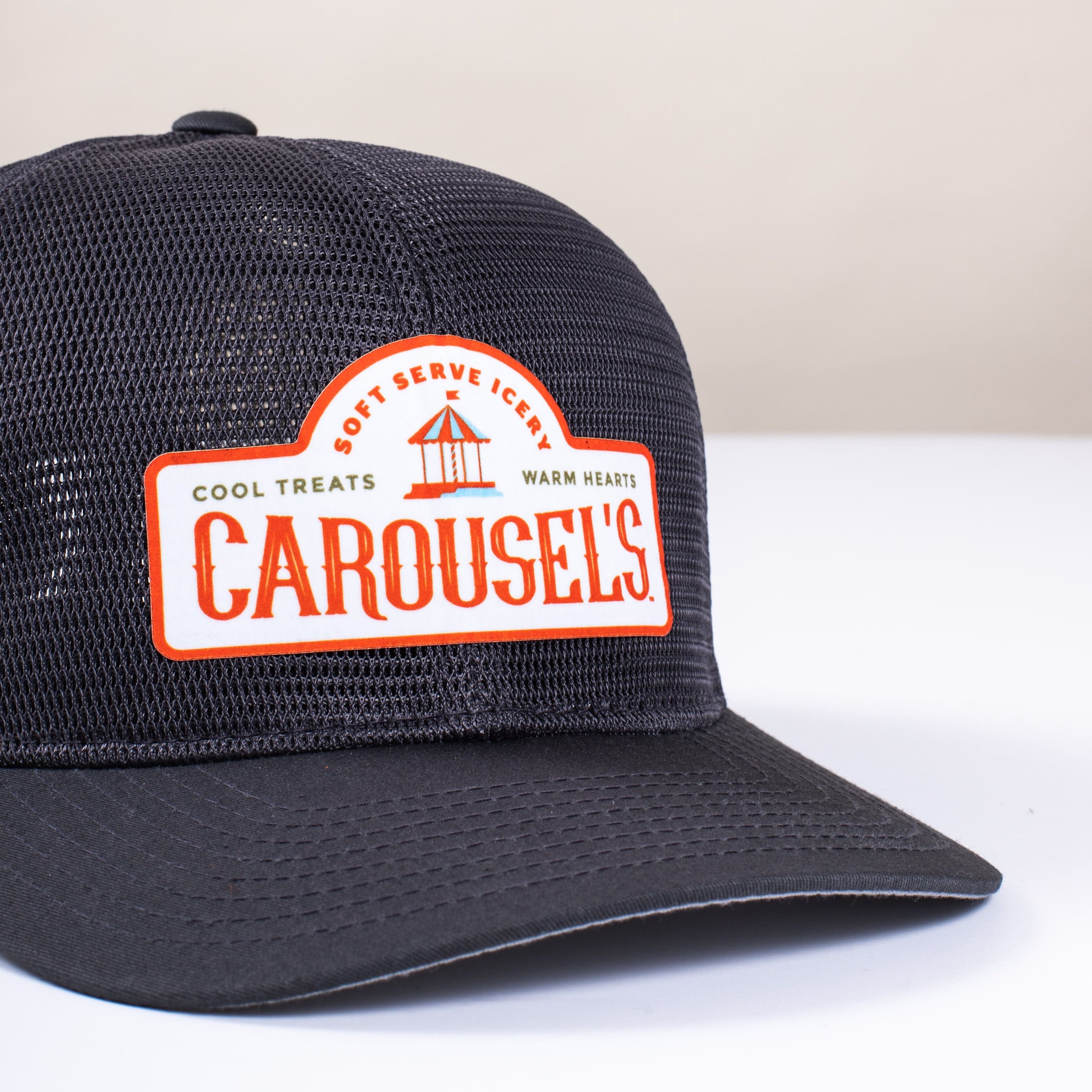 A dark blue trucker hat with a heat pressed patch on the front of it