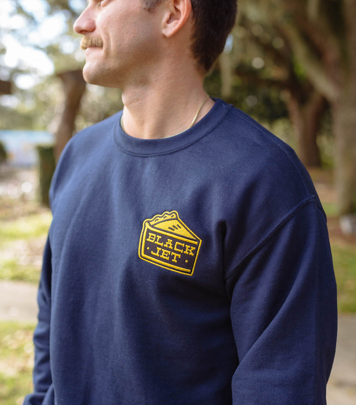 Man wearing a blue sweatshirt with an embroidered patch on it