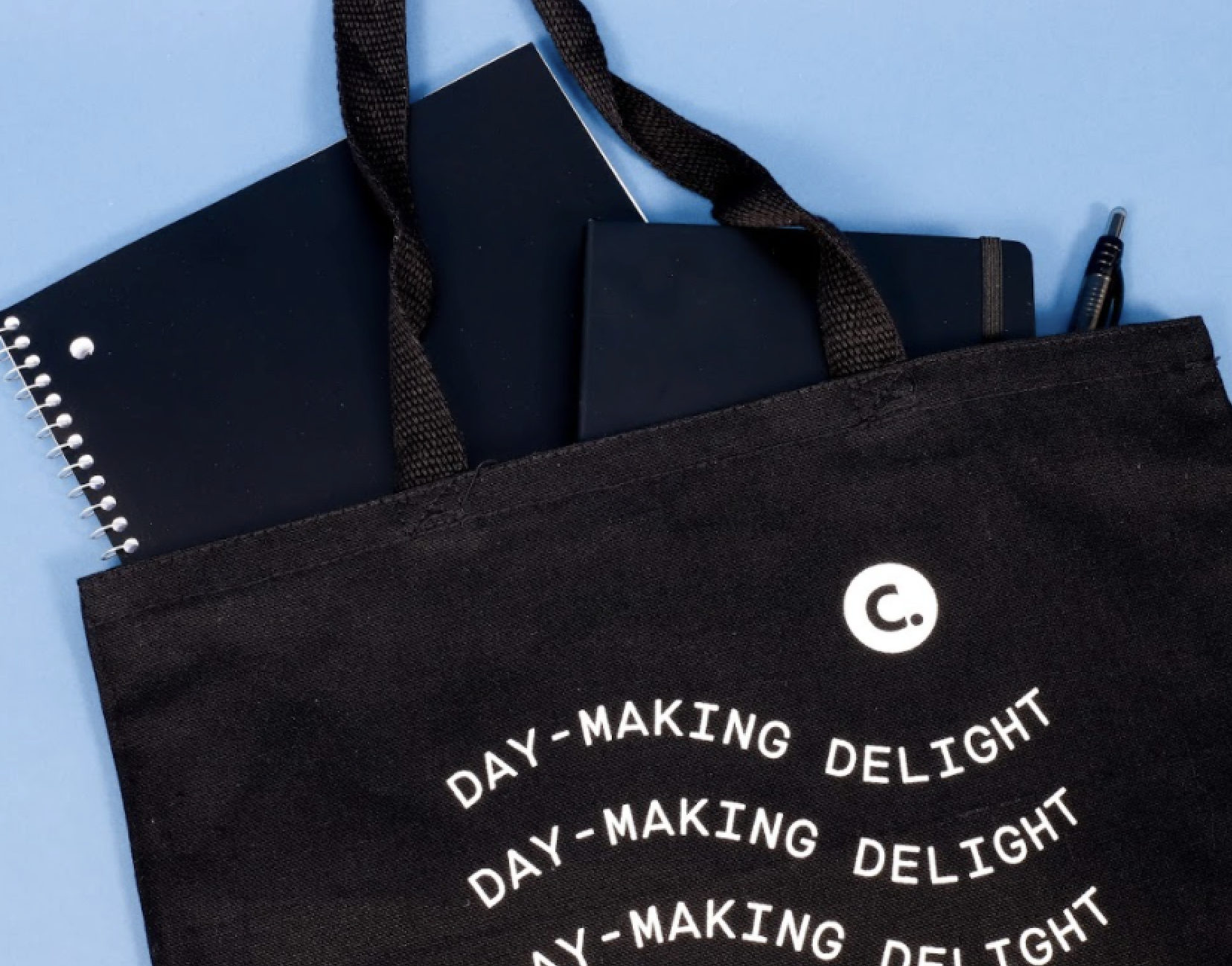 A Corkcicle tote bag filled with pens, notebook, and more.